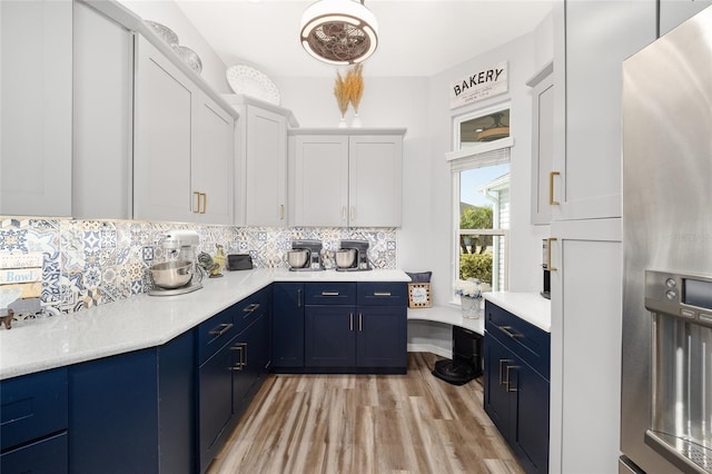 kitchen featuring blue cabinetry, light wood-type flooring, decorative backsplash, stainless steel refrigerator with ice dispenser, and white cabinetry