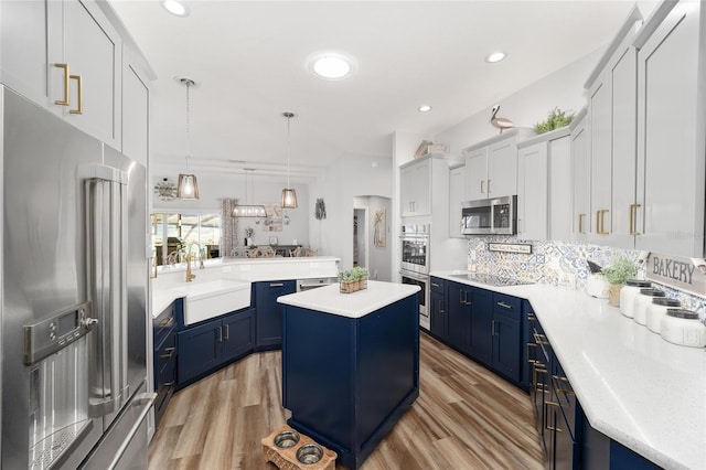 kitchen with appliances with stainless steel finishes, a center island, pendant lighting, sink, and white cabinetry