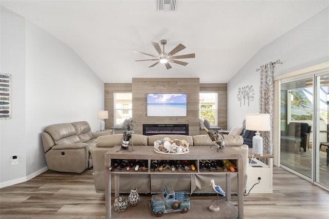 living room with wood-type flooring, a fireplace, ceiling fan, and vaulted ceiling