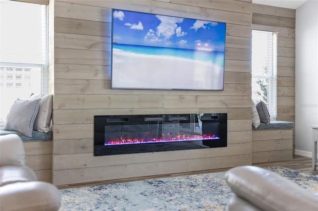 living room with wood-type flooring, wooden walls, and a large fireplace