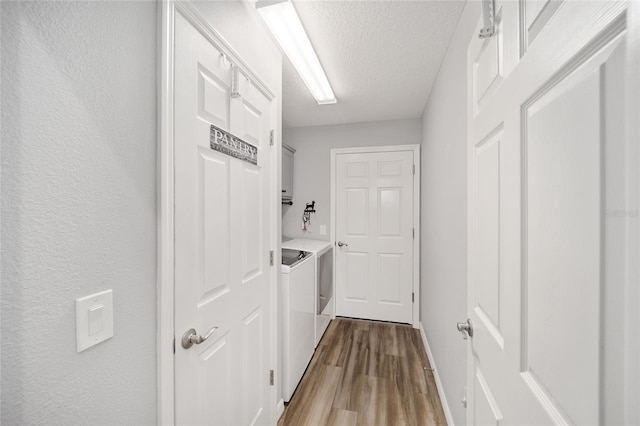 hallway featuring washer and clothes dryer, a textured ceiling, and light wood-type flooring