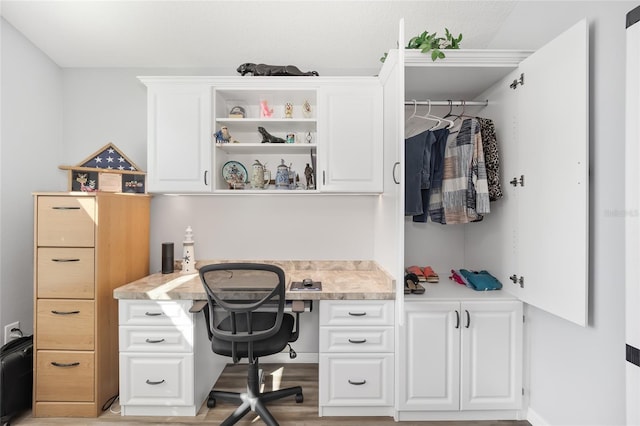 office with built in desk and light hardwood / wood-style flooring