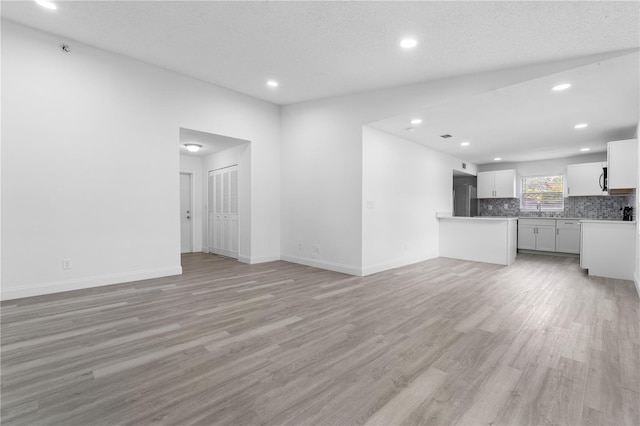 unfurnished living room featuring light hardwood / wood-style floors and a textured ceiling