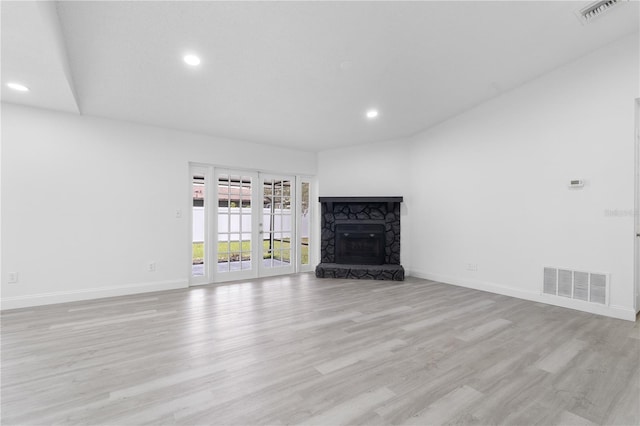 unfurnished living room featuring a stone fireplace and light hardwood / wood-style flooring