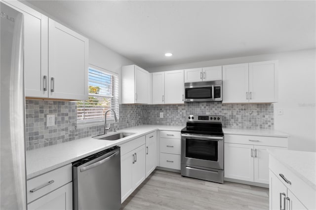 kitchen featuring decorative backsplash, stainless steel appliances, white cabinetry, and sink