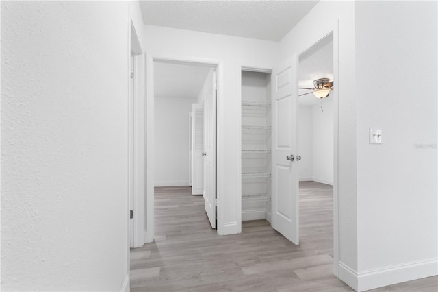 hall with light wood-type flooring and a textured ceiling