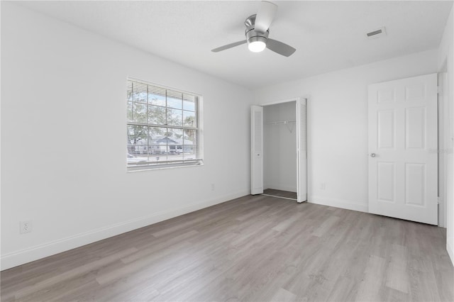 unfurnished bedroom with ceiling fan, light wood-type flooring, and a closet