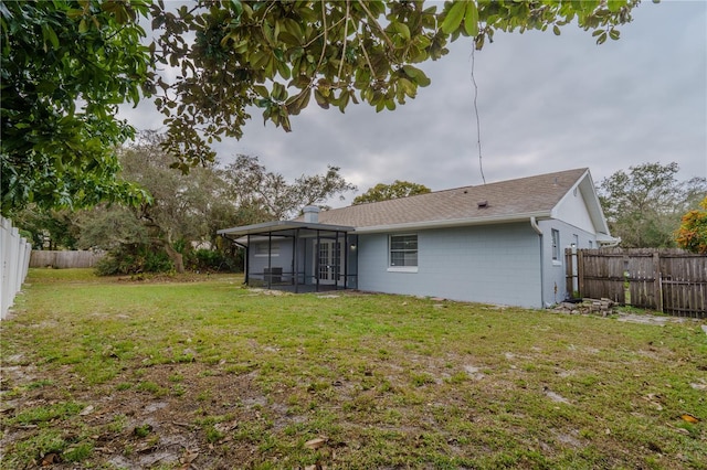 back of house featuring a sunroom and a lawn