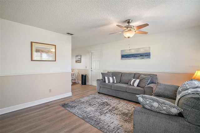 living room with ceiling fan, dark hardwood / wood-style flooring, and a textured ceiling