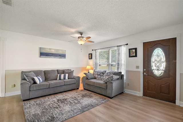 living room with ceiling fan, wood-type flooring, and a textured ceiling