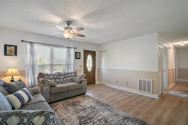 living room featuring ceiling fan, wood-type flooring, and a textured ceiling