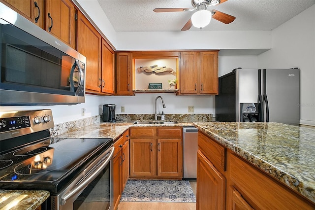 kitchen featuring appliances with stainless steel finishes, a textured ceiling, stone countertops, and sink