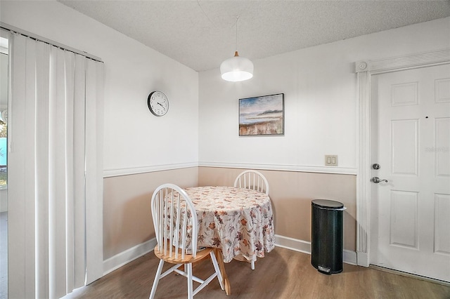 dining space with hardwood / wood-style floors and a textured ceiling