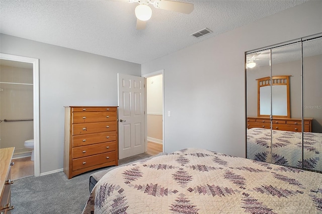 carpeted bedroom featuring connected bathroom, a textured ceiling, a closet, and ceiling fan