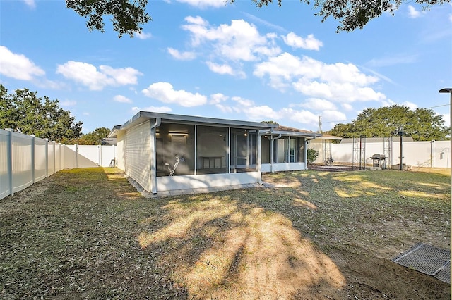 back of property with a sunroom and a lawn