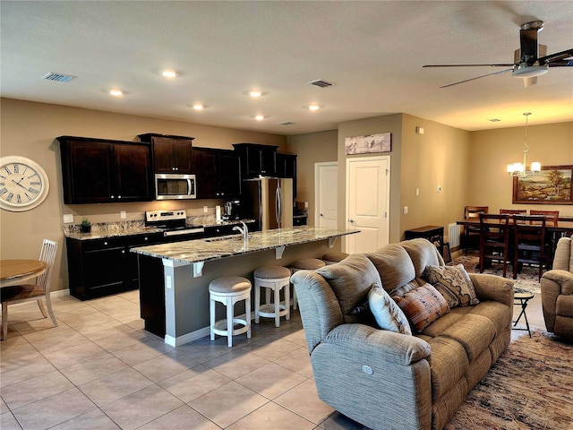 kitchen with a kitchen breakfast bar, light tile patterned floors, an island with sink, and appliances with stainless steel finishes