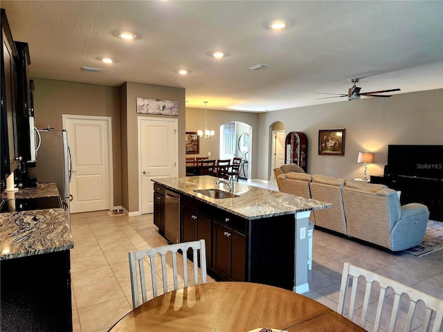 kitchen with pendant lighting, sink, stainless steel dishwasher, light stone countertops, and an island with sink