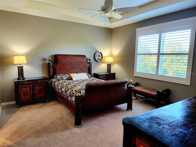 carpeted bedroom featuring a tray ceiling and ceiling fan