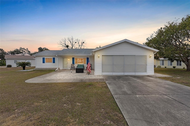 ranch-style house with a patio, a garage, and a lawn