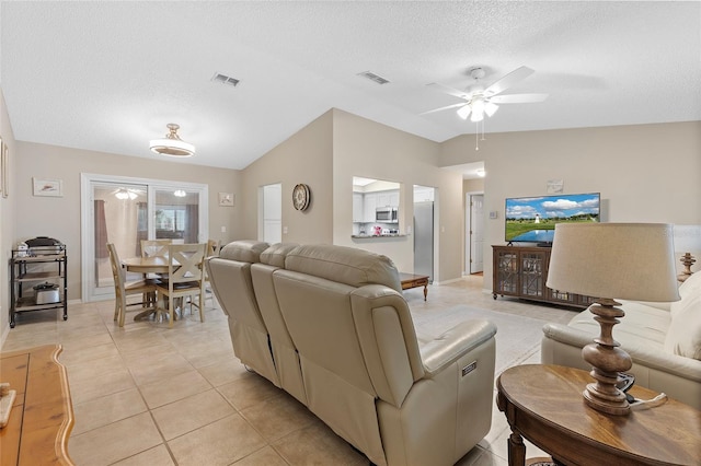 living room featuring a textured ceiling, ceiling fan, light tile patterned flooring, and vaulted ceiling