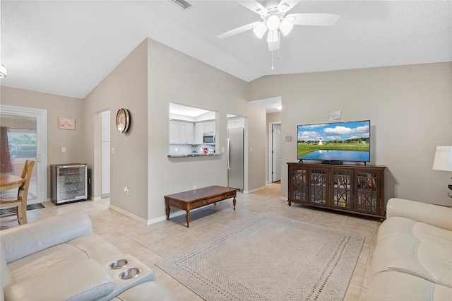 living room with wine cooler, ceiling fan, light tile patterned floors, and lofted ceiling