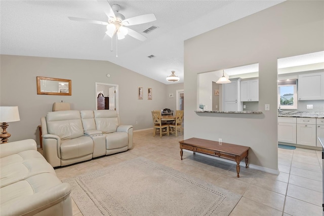 tiled living room featuring a textured ceiling, ceiling fan, and lofted ceiling