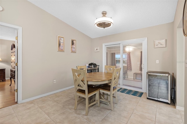 dining area with lofted ceiling, light tile patterned floors, and a textured ceiling