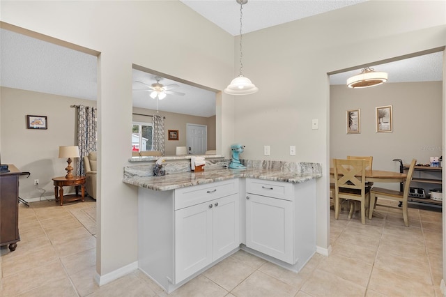 kitchen featuring kitchen peninsula, white cabinetry, ceiling fan, and light stone counters