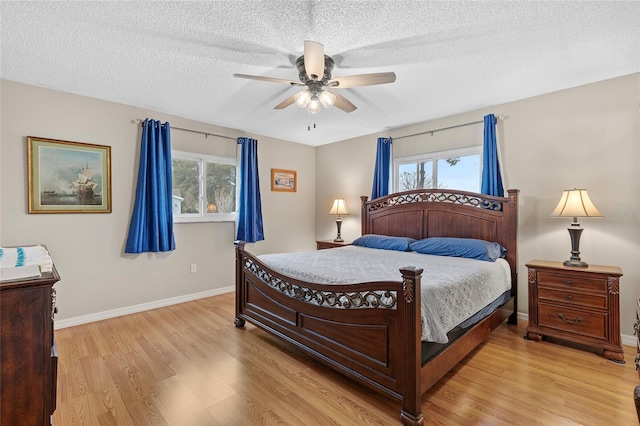 bedroom with ceiling fan, light wood-type flooring, and a textured ceiling