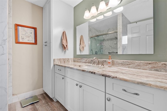 bathroom featuring vanity, wood-type flooring, and a shower with door