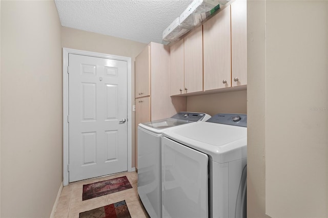 clothes washing area featuring cabinets, light tile patterned flooring, washing machine and dryer, and a textured ceiling