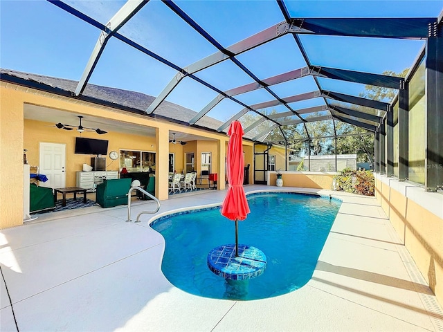 view of swimming pool featuring glass enclosure, ceiling fan, a patio area, and an outdoor hangout area