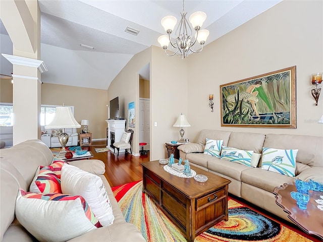 living room with hardwood / wood-style flooring, a notable chandelier, lofted ceiling, and ornate columns