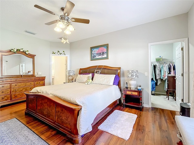 bedroom featuring dark hardwood / wood-style floors, ceiling fan, a walk in closet, and a closet