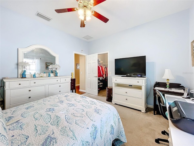 carpeted bedroom with a walk in closet, ceiling fan, and a closet