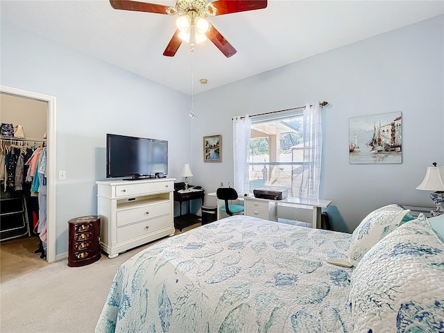 carpeted bedroom featuring a walk in closet, a closet, and ceiling fan