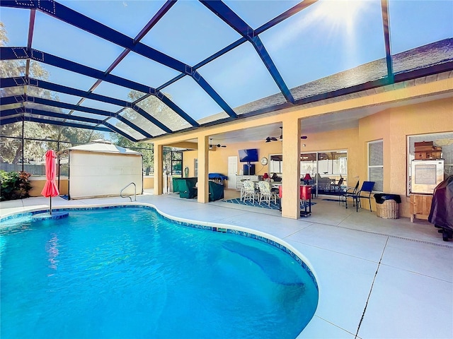 view of swimming pool with glass enclosure, ceiling fan, and a patio area