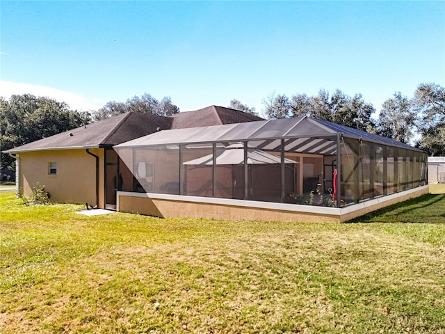 back of property featuring glass enclosure and a lawn