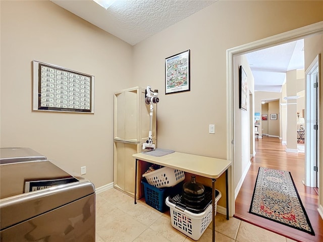 clothes washing area with light tile patterned floors, washer and dryer, and a textured ceiling