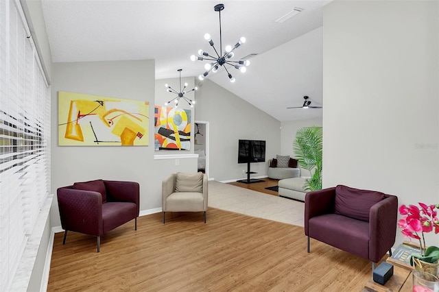 living area with ceiling fan with notable chandelier, light hardwood / wood-style floors, and lofted ceiling