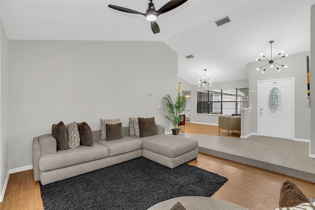 living room featuring ceiling fan with notable chandelier, light wood-type flooring, and lofted ceiling