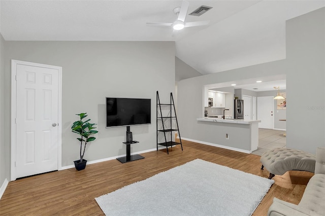 living room featuring light hardwood / wood-style flooring, ceiling fan, lofted ceiling, and sink