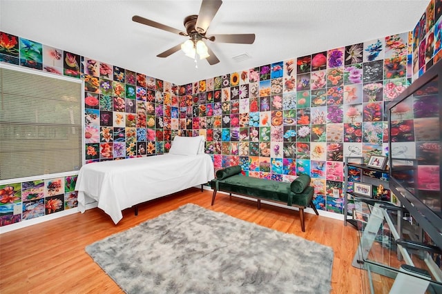 bedroom featuring ceiling fan, wood-type flooring, and a textured ceiling