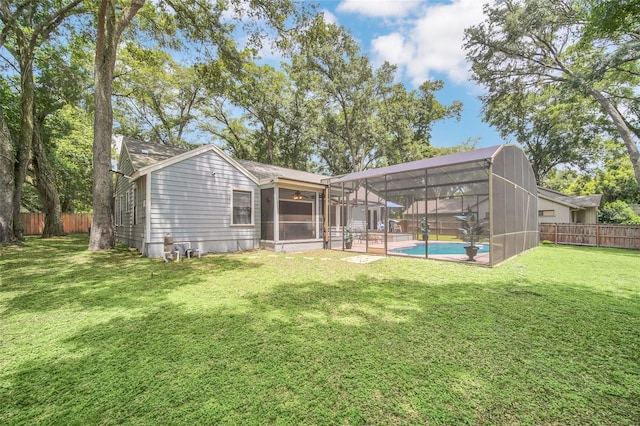 rear view of property featuring a lanai, a patio area, a lawn, and a fenced in pool