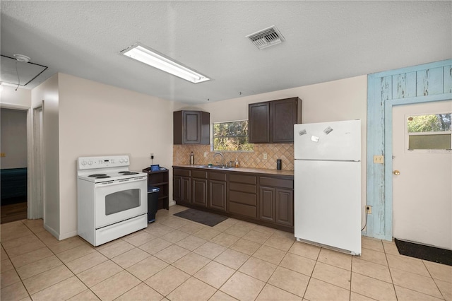 kitchen featuring dark brown cabinetry, sink, plenty of natural light, white appliances, and light tile patterned floors