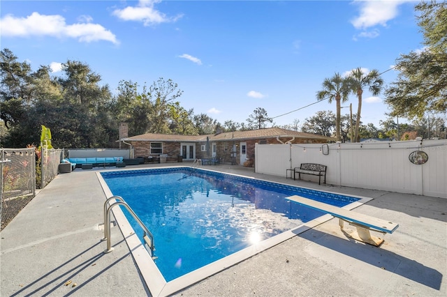 view of swimming pool with an outdoor living space, a diving board, and a patio