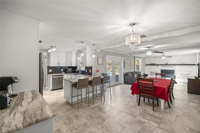 dining area with french doors, ornamental molding, ceiling fan with notable chandelier, a textured ceiling, and sink