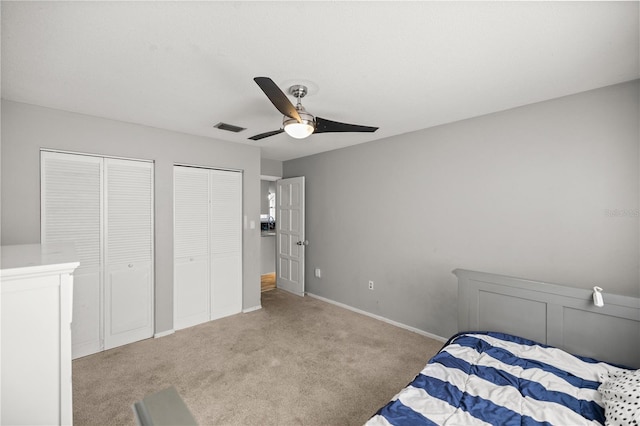 carpeted bedroom featuring multiple closets and ceiling fan