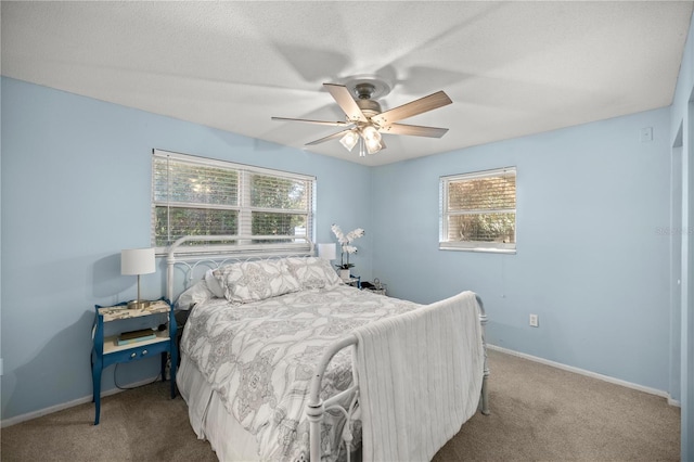 carpeted bedroom with ceiling fan, a textured ceiling, and multiple windows