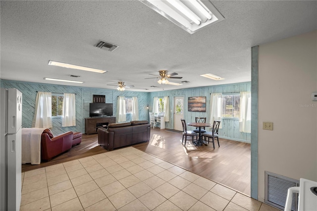 living room featuring a skylight, visible vents, a textured ceiling, and light tile patterned floors